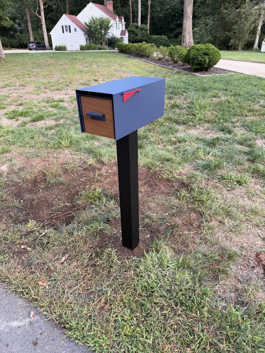 Modern locking mailbox in grey and wood on a black steel post
